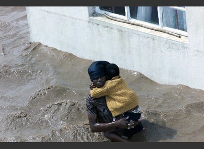 A woman, surrounded by flood waters, holds her baby outside a home in Chibuti, northern Mozambique. | © AP Photo / Themba Hadebe