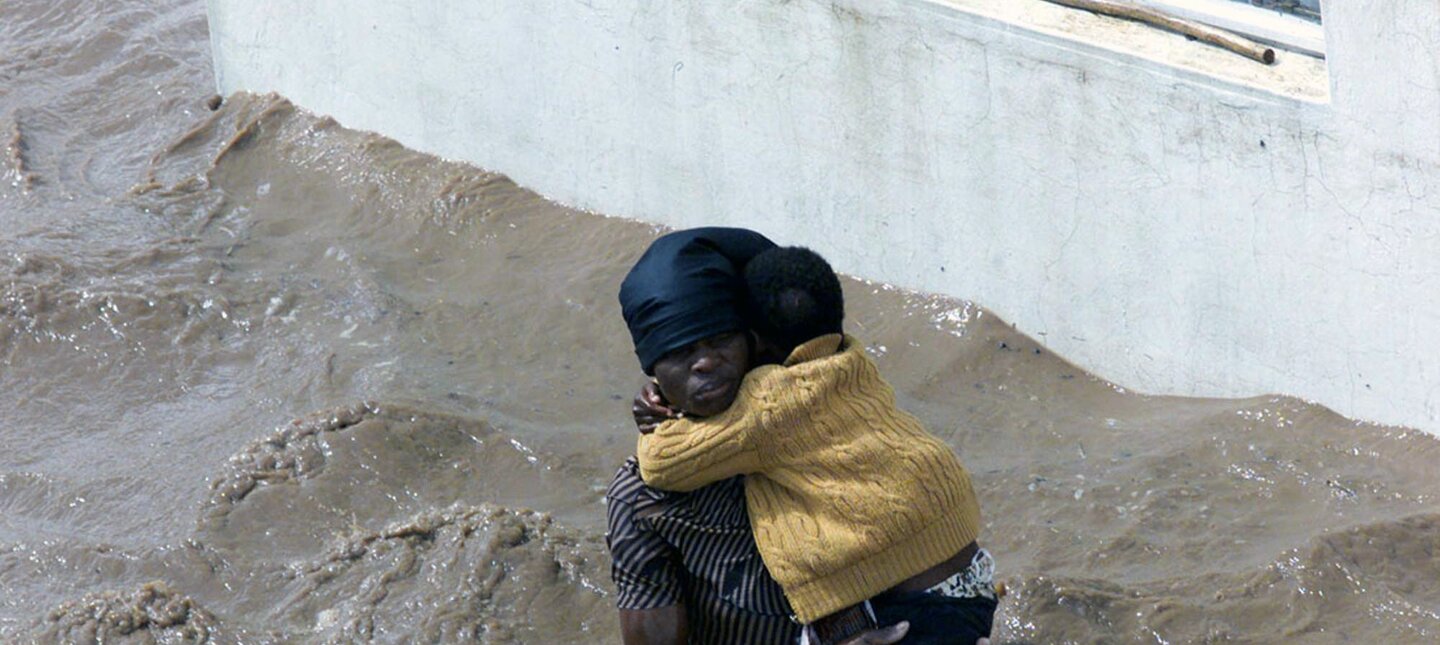 A woman, surrounded by flood waters, holds her baby outside a home in Chibuti, northern Mozambique. | © AP Photo / Themba Hadebe